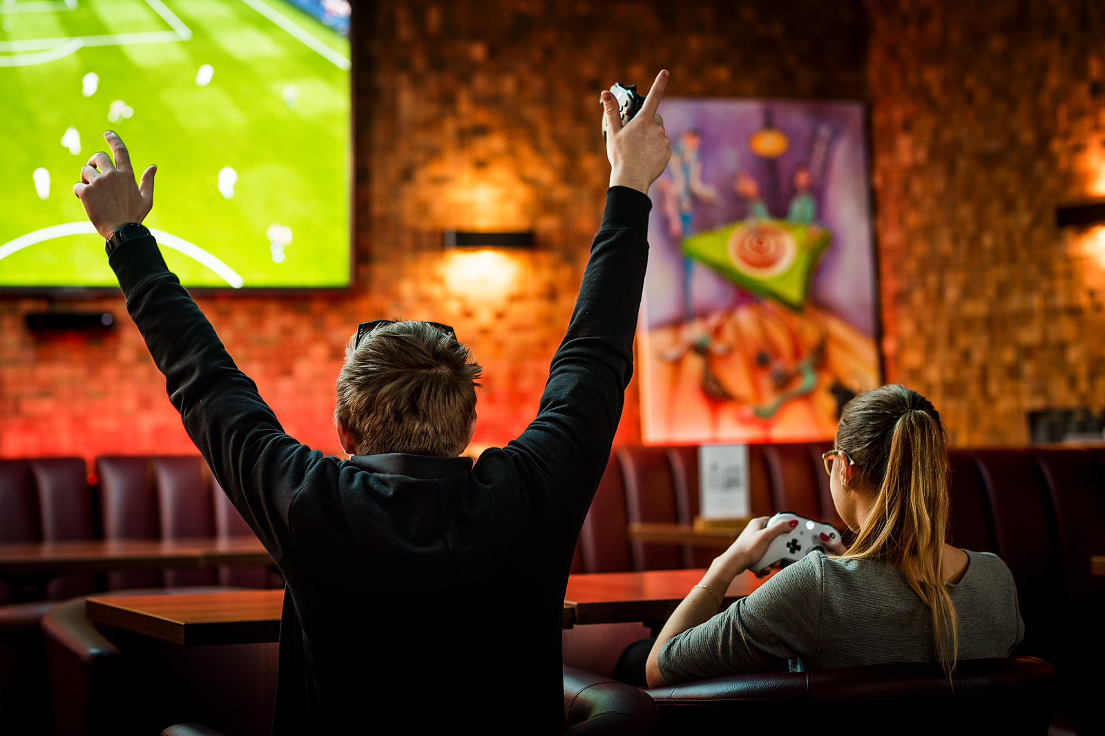 Goście grający na Xboxie na dużym ekranie w Klubie Pictures